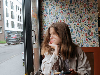 Portrait of a young girl sitting at the window of the cafe