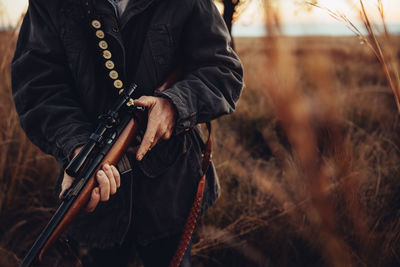 Midsection of hunter with sniper on field