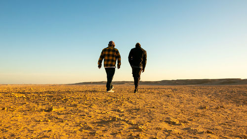 Rear view of woman walking on field