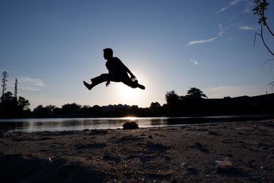 Low angle view of man standing on beach against sky during sunset