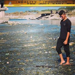 Side view of young man standing in water