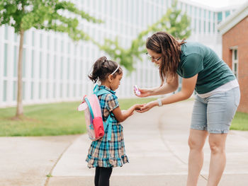 Young millennial mother sending daughter off back to school