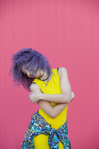 Smiling woman with curly hair dancing against wall