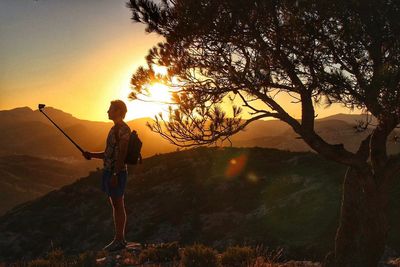 Full length of man by tree at sunset