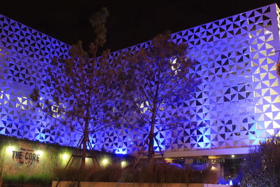 Low angle view of illuminated trees against blue sky