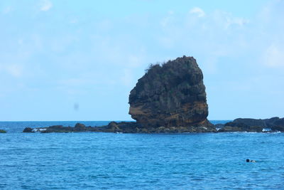 Rock formation in sea against sky