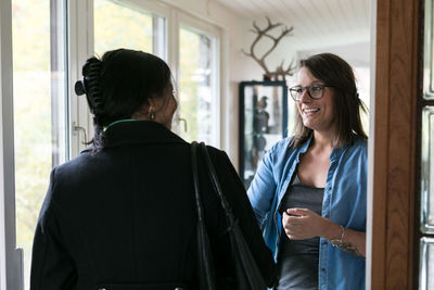 Rear view of businesswoman greeting female colleague at home office