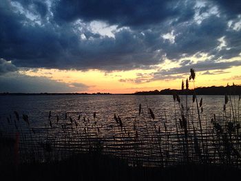 Scenic view of sea against cloudy sky at sunset