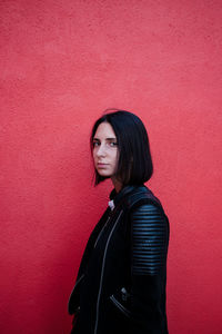 Portrait of young woman standing against red background