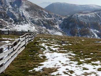 Fence on field against mountains during winter