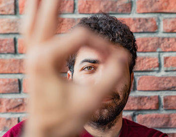 Close-up portrait of man against brick wall