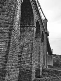 Low angle view of bridge against brick wall