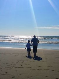 Rear view of friends standing on beach against sea