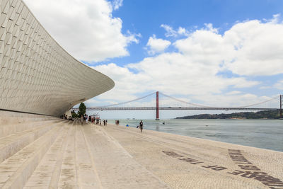 Bridge over sea against cloudy sky