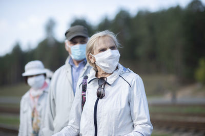 Group of elderly seniors people with face masks waiting train before traveling during a pandemic