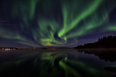 Aurora borealis over river against sky at night