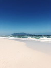 Scenic view of beach against clear blue sky