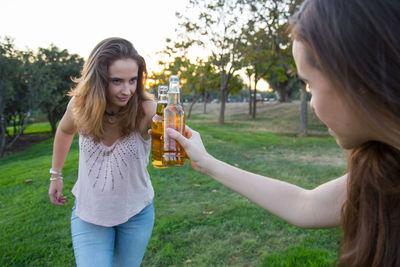 Friends toasting beer bottles at park