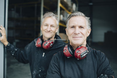 Portrait of smiling workers standing in entrance at industry