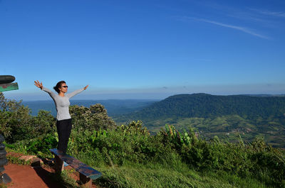 Man standing on mountain by road against sky