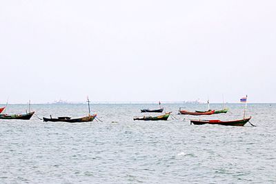 Boats moored on sea against clear sky