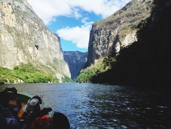 People in boat on river against mountains