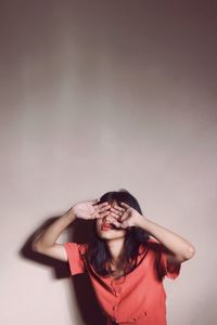 Portrait of beautiful young woman against wall