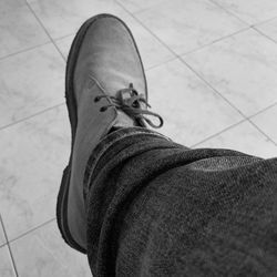 Low section of person wearing canvas shoes on tiled floor