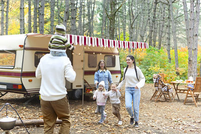 Full length of people standing by motor home against trees