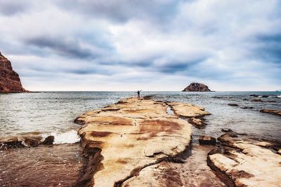 Rock formation on beach against sky