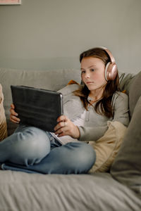 Teenage girl on sofa watching movie through digital tablet at home