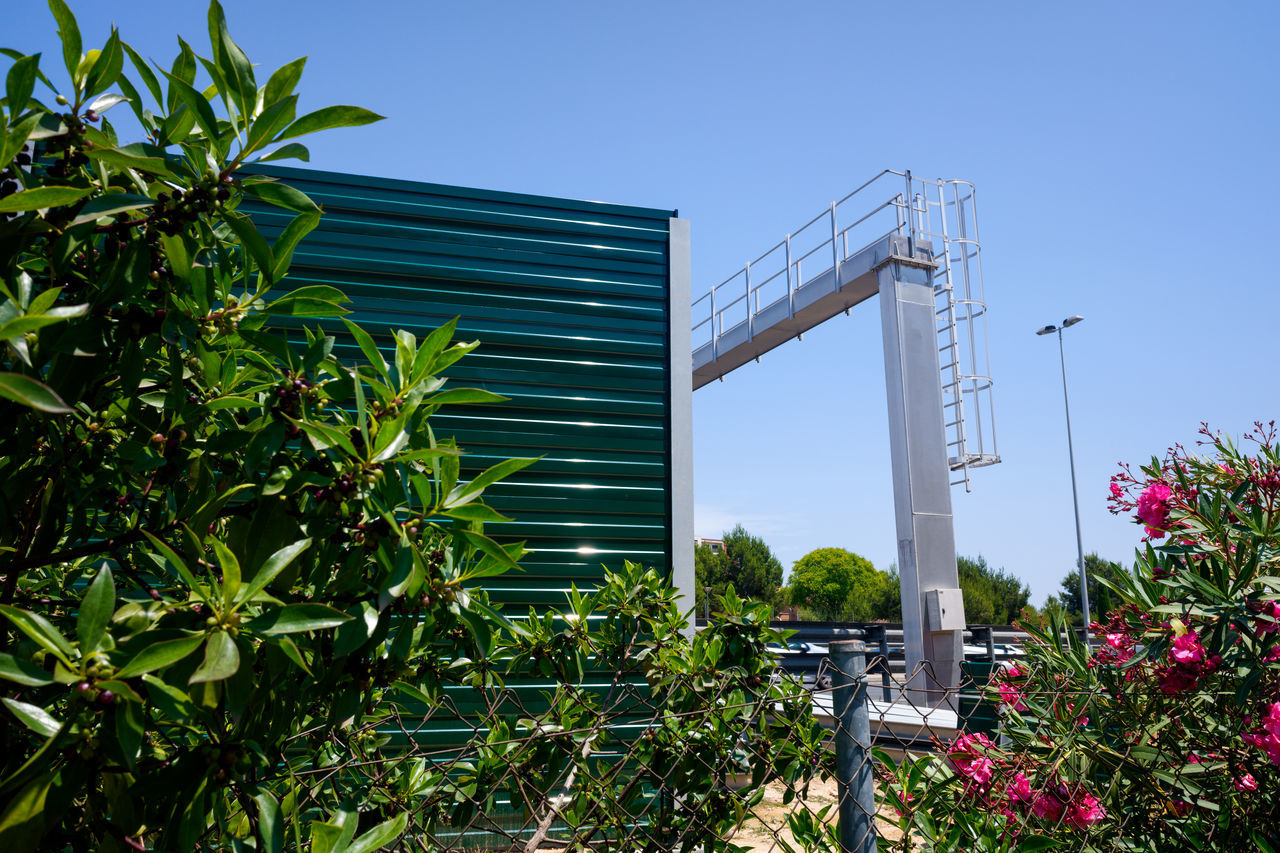 plant, architecture, built structure, nature, building exterior, sky, flower, growth, tree, industry, building, garden, outdoors, no people, blue, day, city, clear sky, leaf, house, environmental conservation, sunny, grass, business, green, plant part, urban area