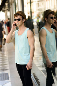 Young man talking on phone while standing by store window