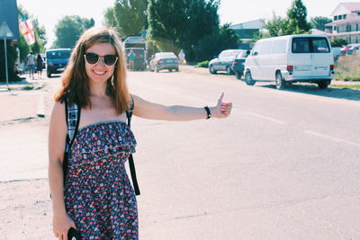 Portrait of woman wearing sunglasses standing on road in city
