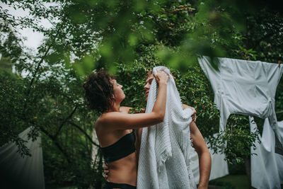 Couple with towel standing against trees