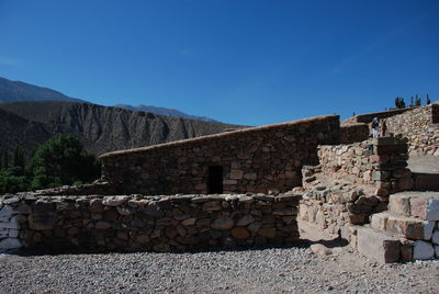 Stack of stone wall against clear blue sky