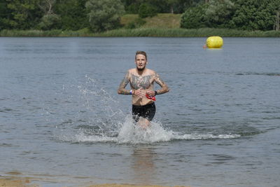 Portrait of shirtless young man walking in sea