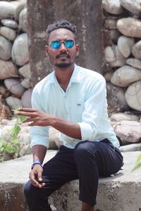 Portrait of young man sitting on rock