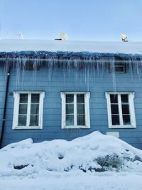 Frozen house against sky during winter