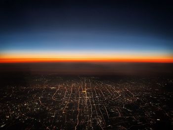 Aerial view of illuminated city against sky at sunset