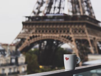 Coffee cup on railing with eiffel tower seen in background