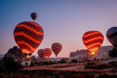 Hot air balloon flying over landscape against sky during sunset