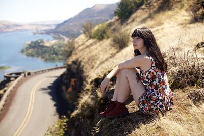 Woman looking away while sitting on land