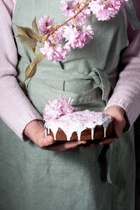 A woman decorates a homemade easter cake with pink sakura flowers,spring blossom