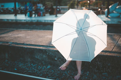 Midsection of woman holding umbrella standing in rain