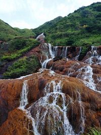 Scenic view of waterfall against sky