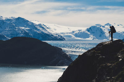 Man standing on rock against snowcapped mountains