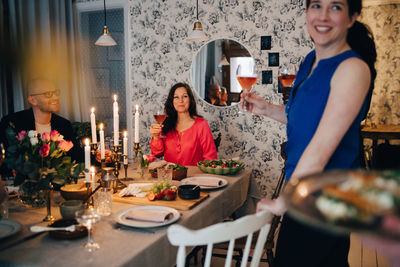 Woman enjoying drinks with friends at dining table in party