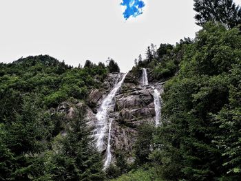 Low angle view of waterfall against sky in forest