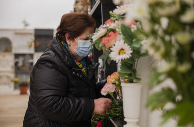 Old lady with mask mourning her family in cemetery. almeria, spain